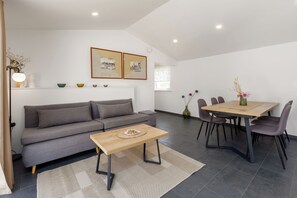 A modern living room with a sofa, coffee table, dining table, chairs, and artwork on the wall. - House Prenc (Sveti Petar u Sumi)