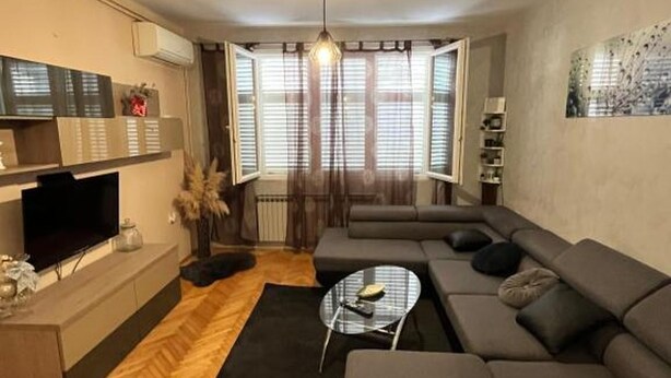 A modern living room with a large sectional sofa, a glass coffee table, and a flat-screen TV on a wooden cabinet. - Apartment Ivana (Makarska)