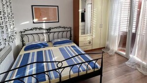 A bedroom with a bed, a wardrobe, a mirror, and a window with curtains. - Apartment Ivana (Makarska)