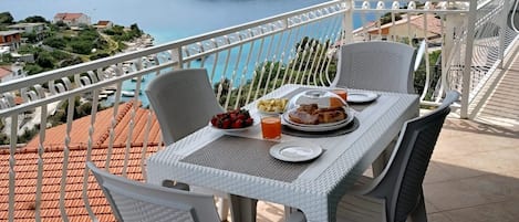 Une terrasse avec une table dressée pour le petit-déjeuner, offrant une vue sur un paysage côtier.