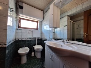 A bathroom with a sink, bidet, toilet, and a window. - Apartments Preden (Crikvenica)