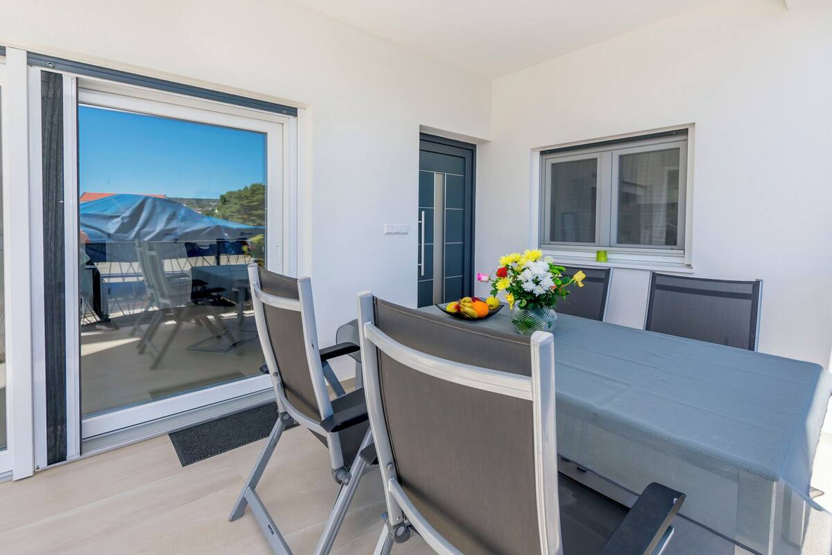 Ein moderner Essbereich mit Glastrennwand, einem Tisch, der mit einem Blumenstrauß gedeckt ist, und Blick ins Freie.