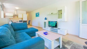 Una sala de estar moderna con un sofá azul, un televisor y una mesita.