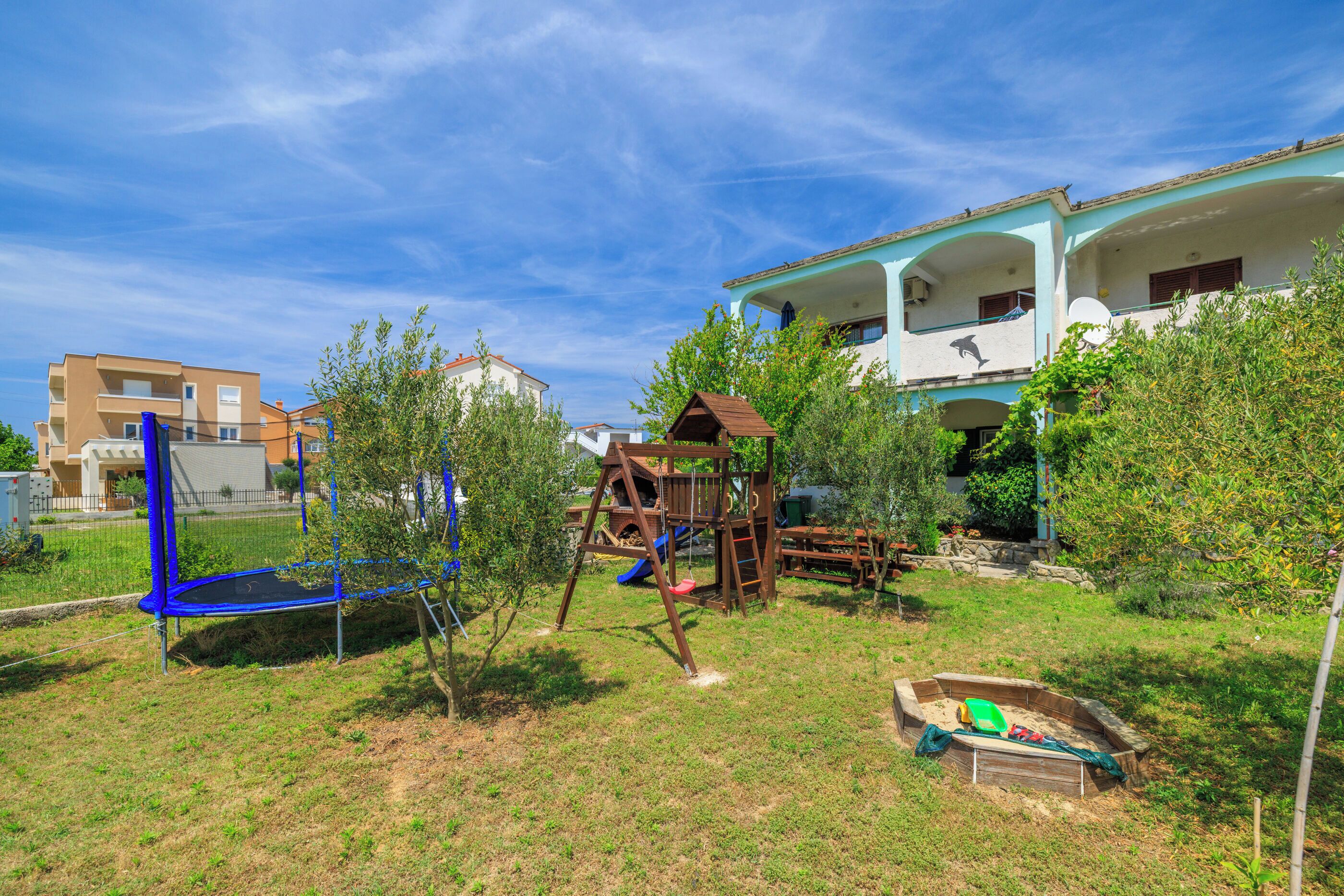 A residential area with a playground, including a swing set and a slide, and a small boat in a sandbox.