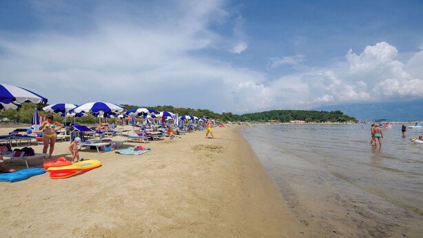 A beach with rows of umbrellas and beach chairs, a sandy shore, and a calm sea. - Apartment M&M (Lopar)