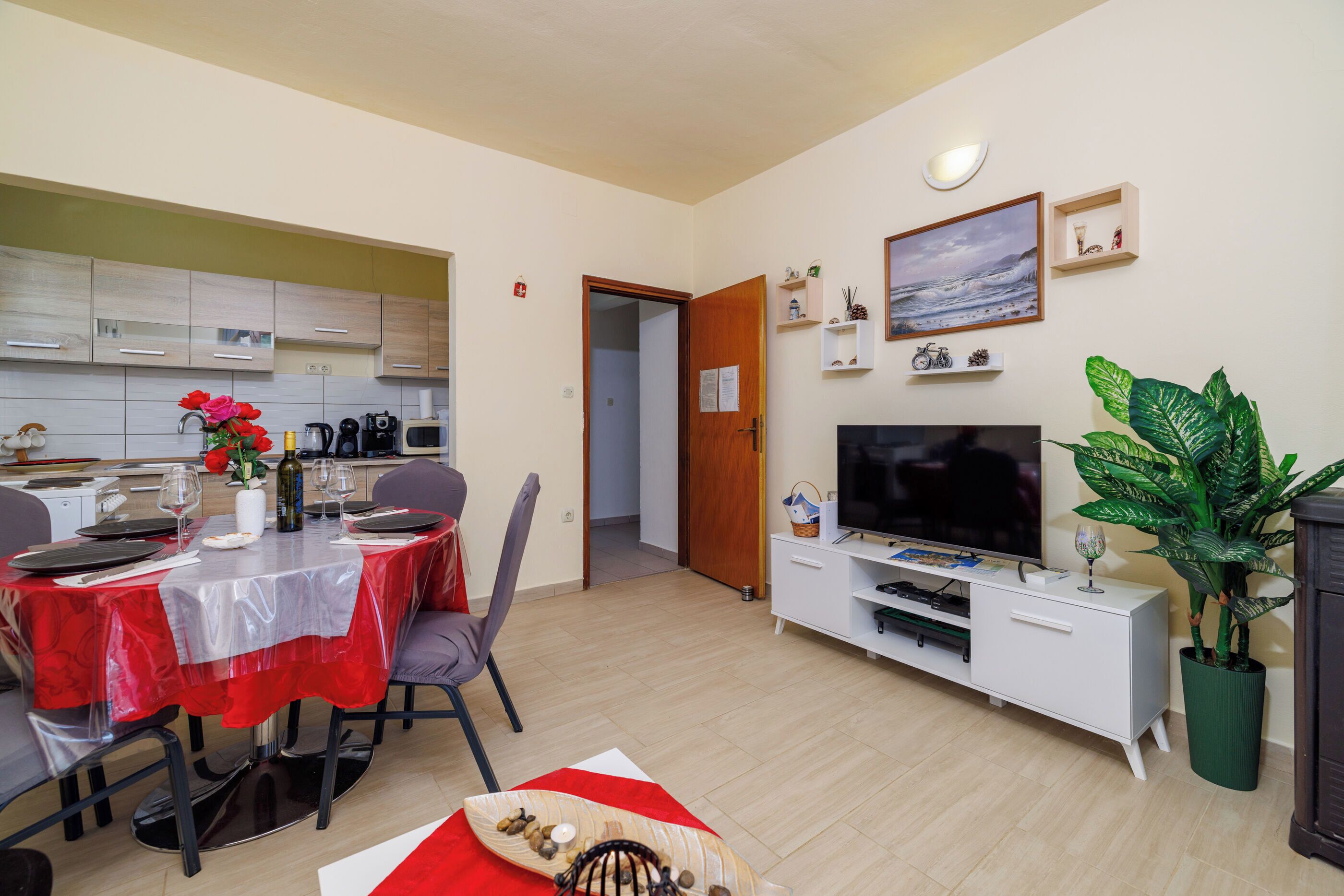 Un salon moderne comprenant un coin repas, un téléviseur à écran plat, une plante en pot et un meuble en bois.