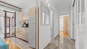 A modern kitchen with wooden cabinets, a refrigerator, and a countertop with a coffee machine. - Apartments Vera (Porec)