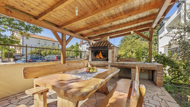 An outdoor wooden pergola with a brick oven and a wooden table with benches. - Apartments Vera (Porec)