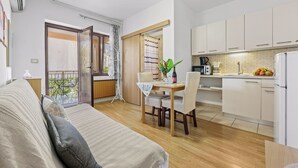 A modern kitchen with white cabinets, a dining area with a table and chairs, and a balcony with a view. - Apartments Vera (Porec)