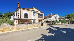 A two-story house with a stone wall, a balcony, and a garage. - Apartments Vera (Porec)