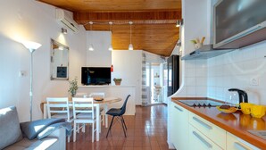 Eine moderne Küche mit weißen Schränken, einer Holz Arbeitsplatte und einem eingebauten Backofen. Es gibt einen Essbereich mit Tisch und Stühlen sowie einen an der Wand befestigten Fernseher.