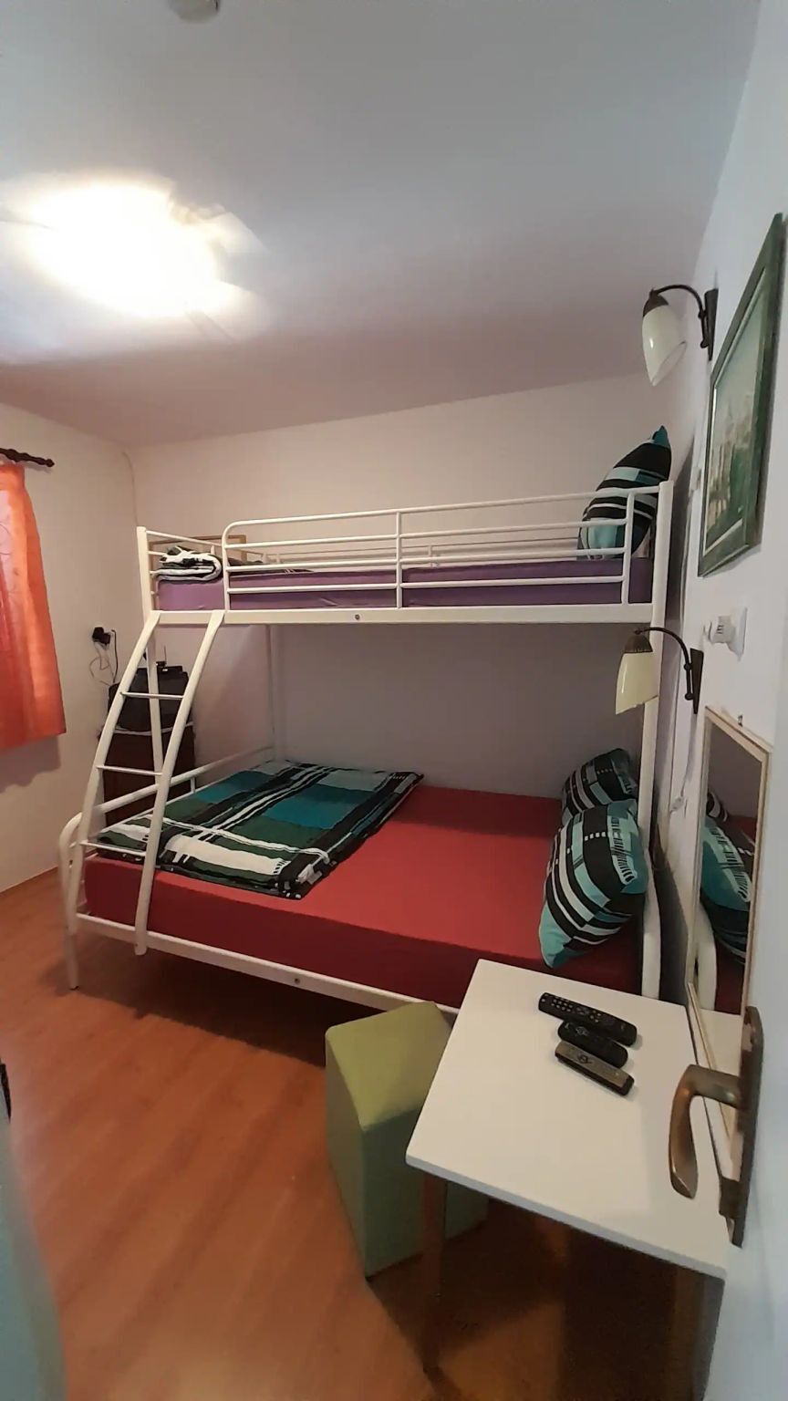 A bunk bed with a desk and a chair, a lamp, and a picture on the wall.
