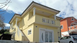 A two-story building with a yellow facade, white trim, and a balcony with white balustrades. - Apartment Sarah (Cavle)