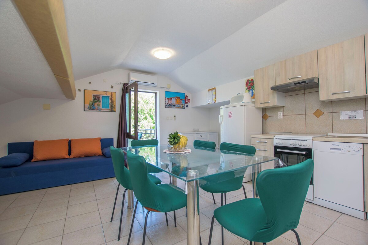 A compact living space with a dining area, kitchenette, and a sofa with orange cushions.
