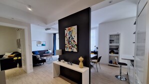 A modern living room with a black accent wall, a white console table, and a dining area with a white cabinet and a dining table. - Apartments Mar (Crikvenica)