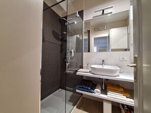 A modern bathroom with a glass-enclosed shower, a white sink, and a mirror above the sink. - Apartments Mar (Crikvenica)