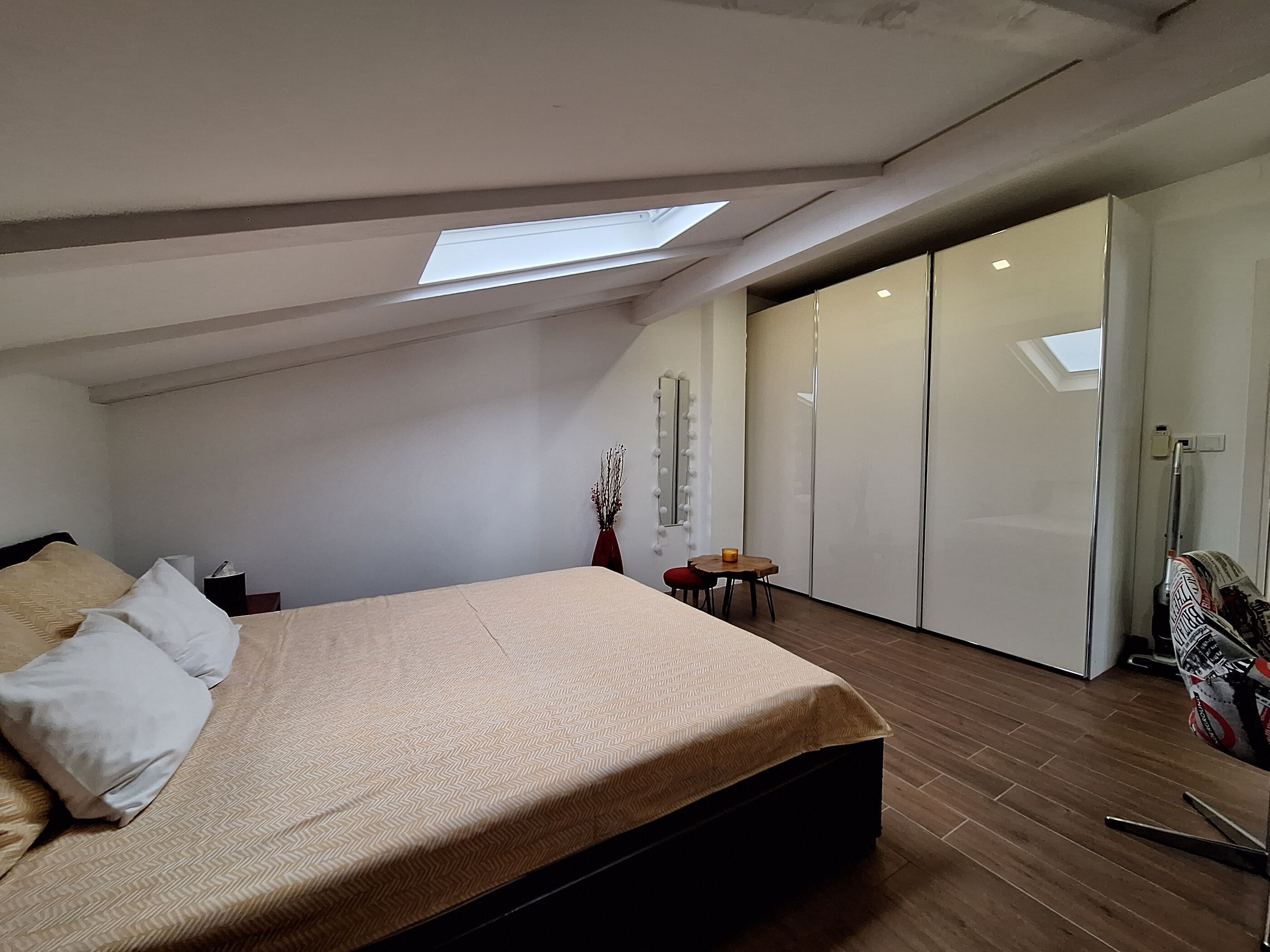 Une chambre à coucher avec un lit, une petite table, un miroir et une armoire.