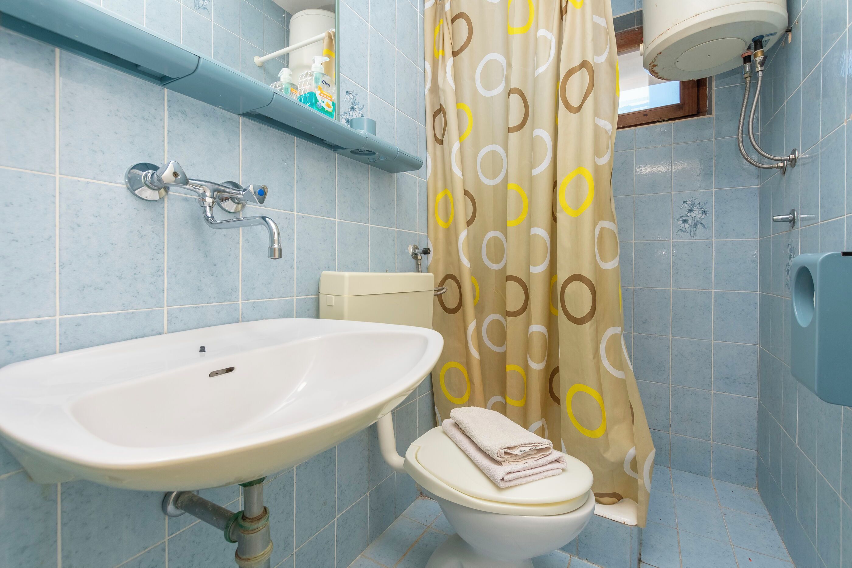 A bathroom with a sink, toilet, shower, and a towel rack.