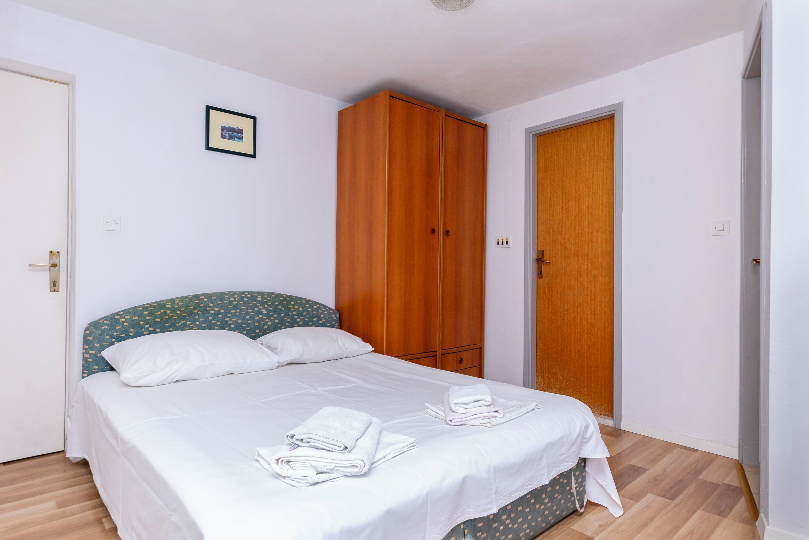 Een slaapkamer met een bed, een kledingkast en een deur.