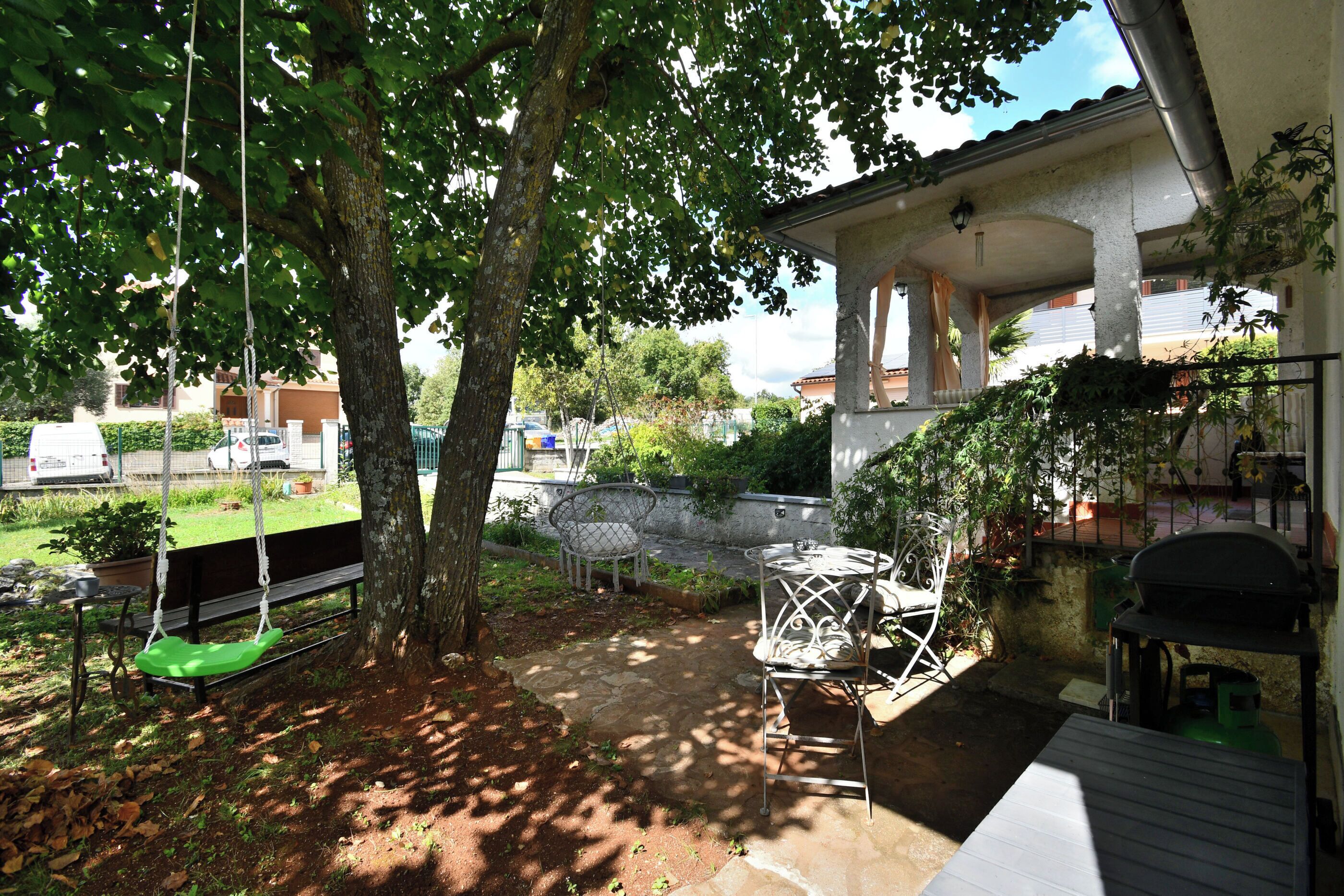 A patio area with a swing, a table, and a grill.