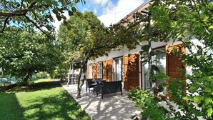 Ein Haus mit Terrasse, Essbereich und Garten.