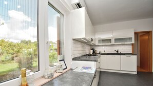 Eine moderne Küche mit weißen Schränken, einer schwarzen Arbeitsplatte und einem Fenster mit Blick auf einen Garten.