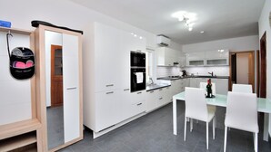 Eine moderne Küche mit weißen Schränken, einem Esstisch mit Stühlen und einem eingebauten Backofen.