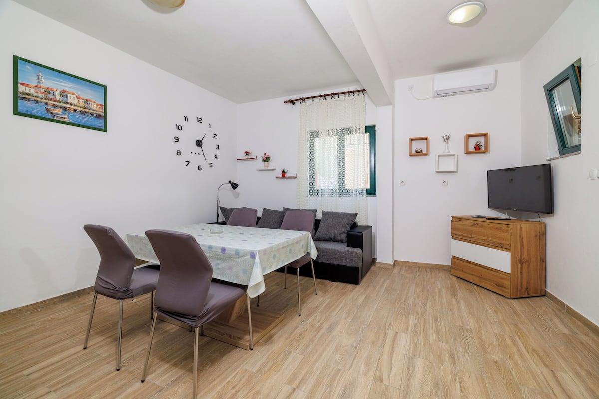 Un salon moderne comprenant une table à manger, des chaises, un canapé, un téléviseur et des objets décoratifs.