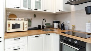 Una cucina moderna con mobili bianchi, un forno a microonde, una macchina da caffè e un piano cottura.