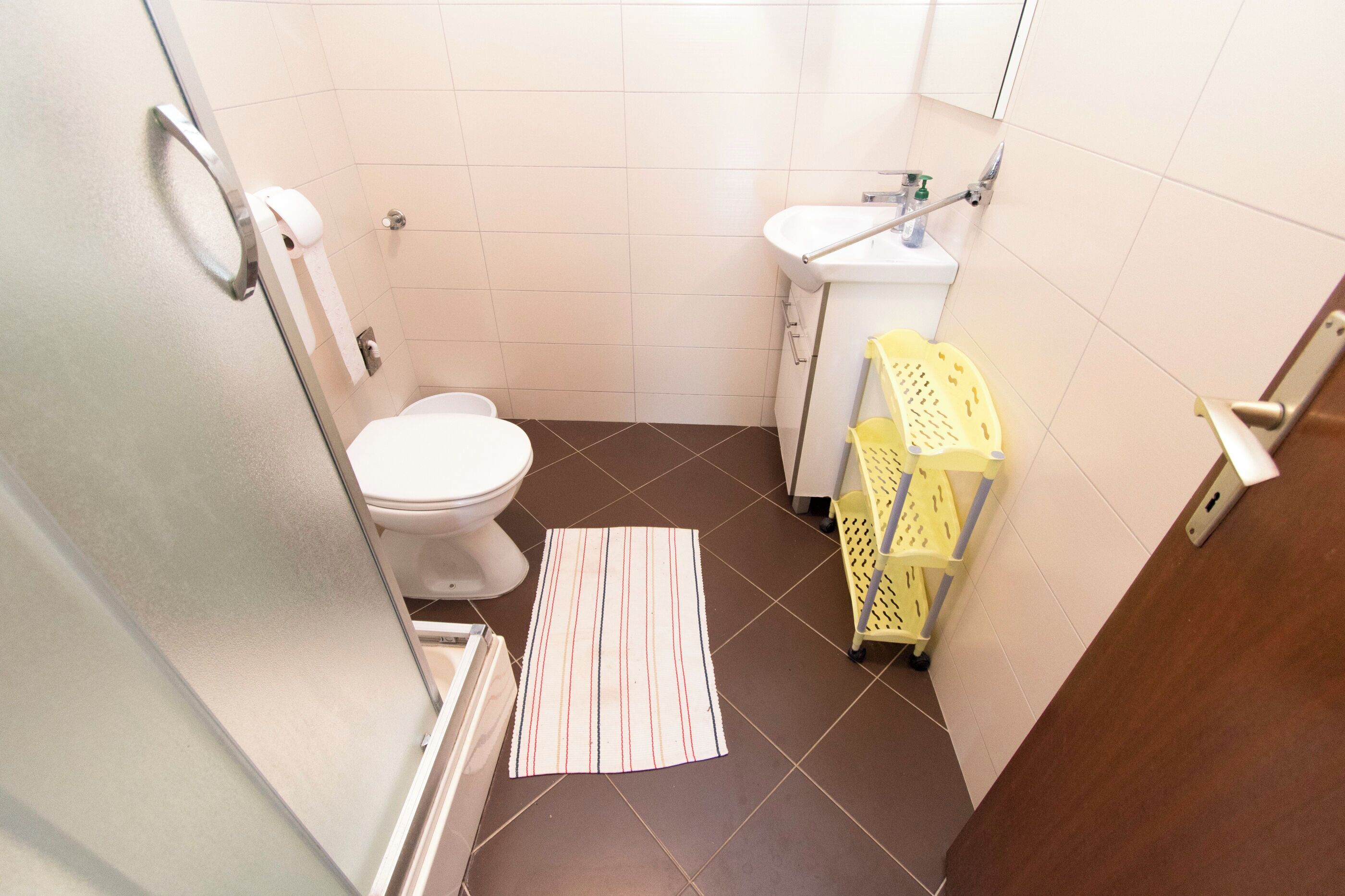 A small bathroom with a toilet, sink, and a yellow cleaning cart.