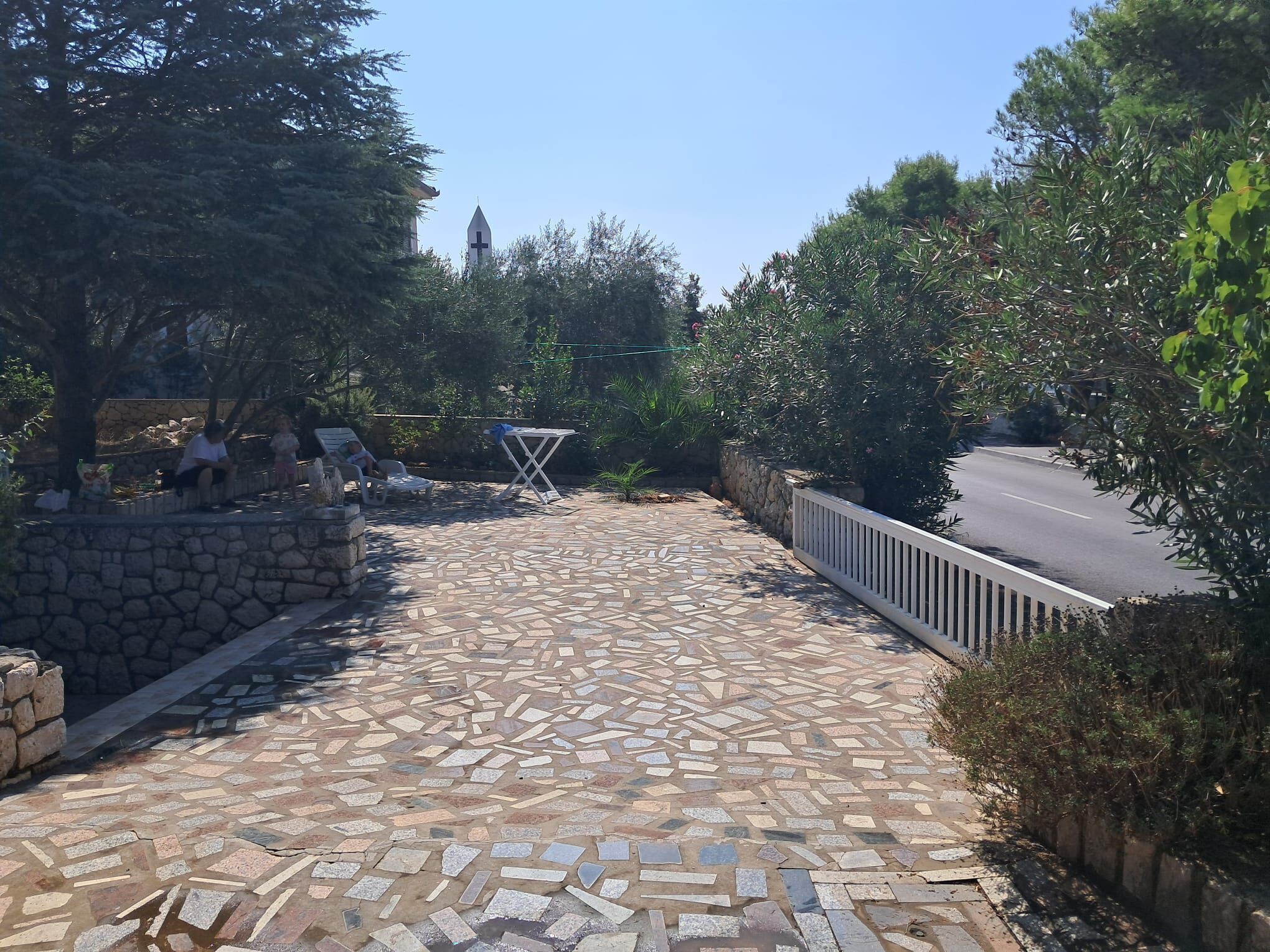 A paved walkway with stone tiles, a stone wall, and a metal fence.
