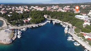 Vue aérienne d’une ville côtière avec un port de plaisance, des immeubles résidentiels et une plage.