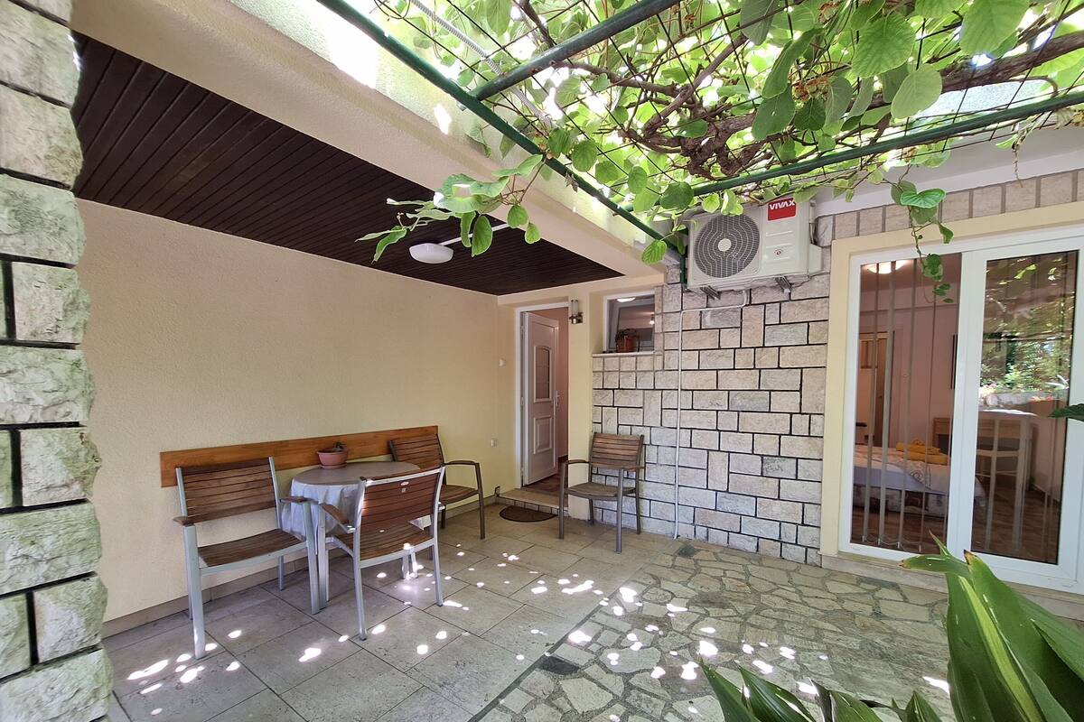 Un espace patio agrémenté d’un mur en pierre, d’un banc en bois, d’une table et de chaises.