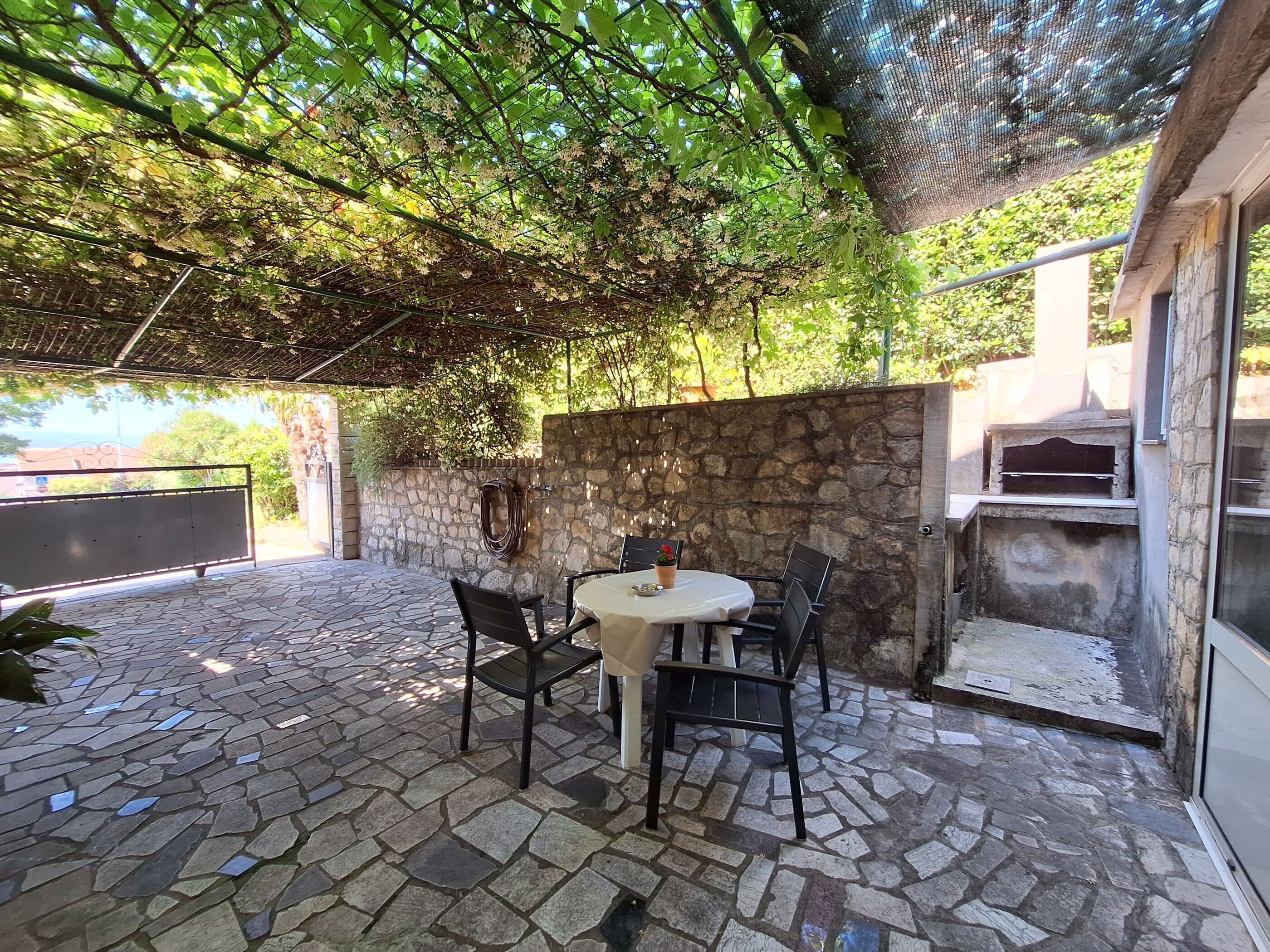 An outdoor patio with stone flooring, a round table, and chairs.