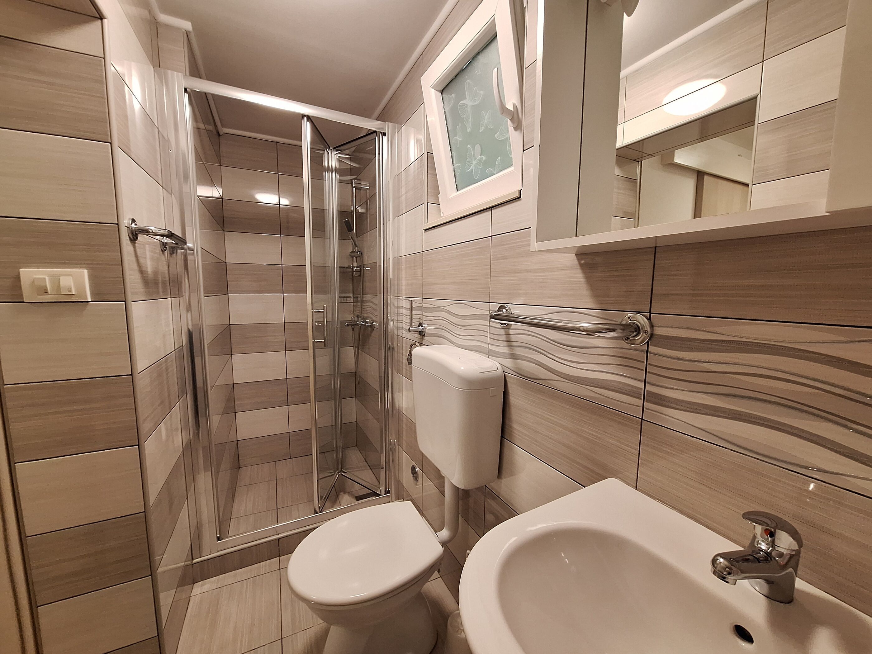 Un baño moderno con ducha de vidrio, inodoro y lavamanos.