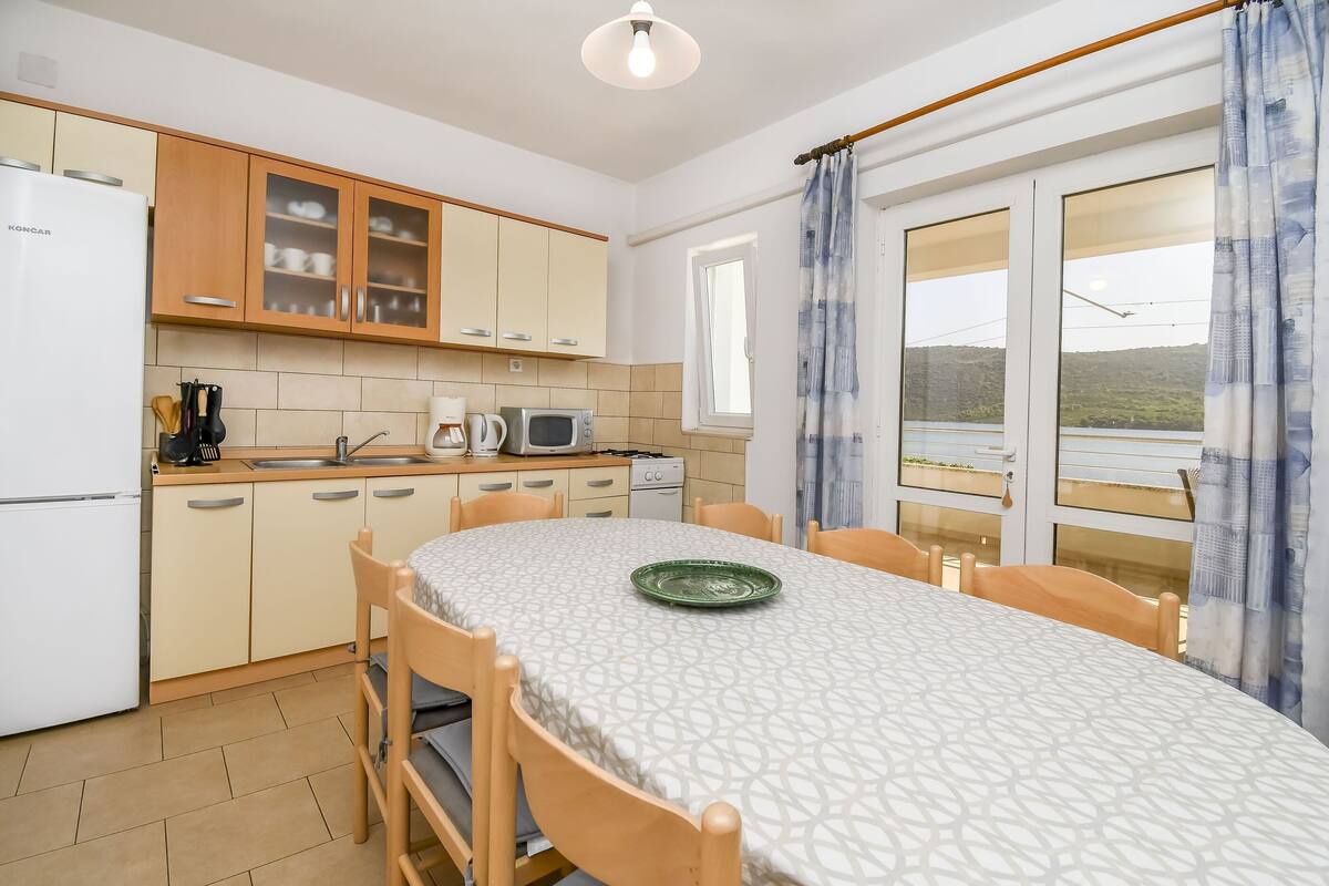 A kitchen with wooden cabinets, a refrigerator, a microwave, and a dining table with chairs.