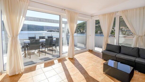 Een balkon met een glazen deur, een bank en een tafel.