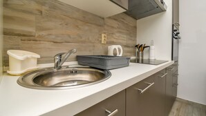 Een moderne keuken met een spoelbak van roestvrij staal, een waterkoker en een koffiezetapparaat op het aanrecht.
