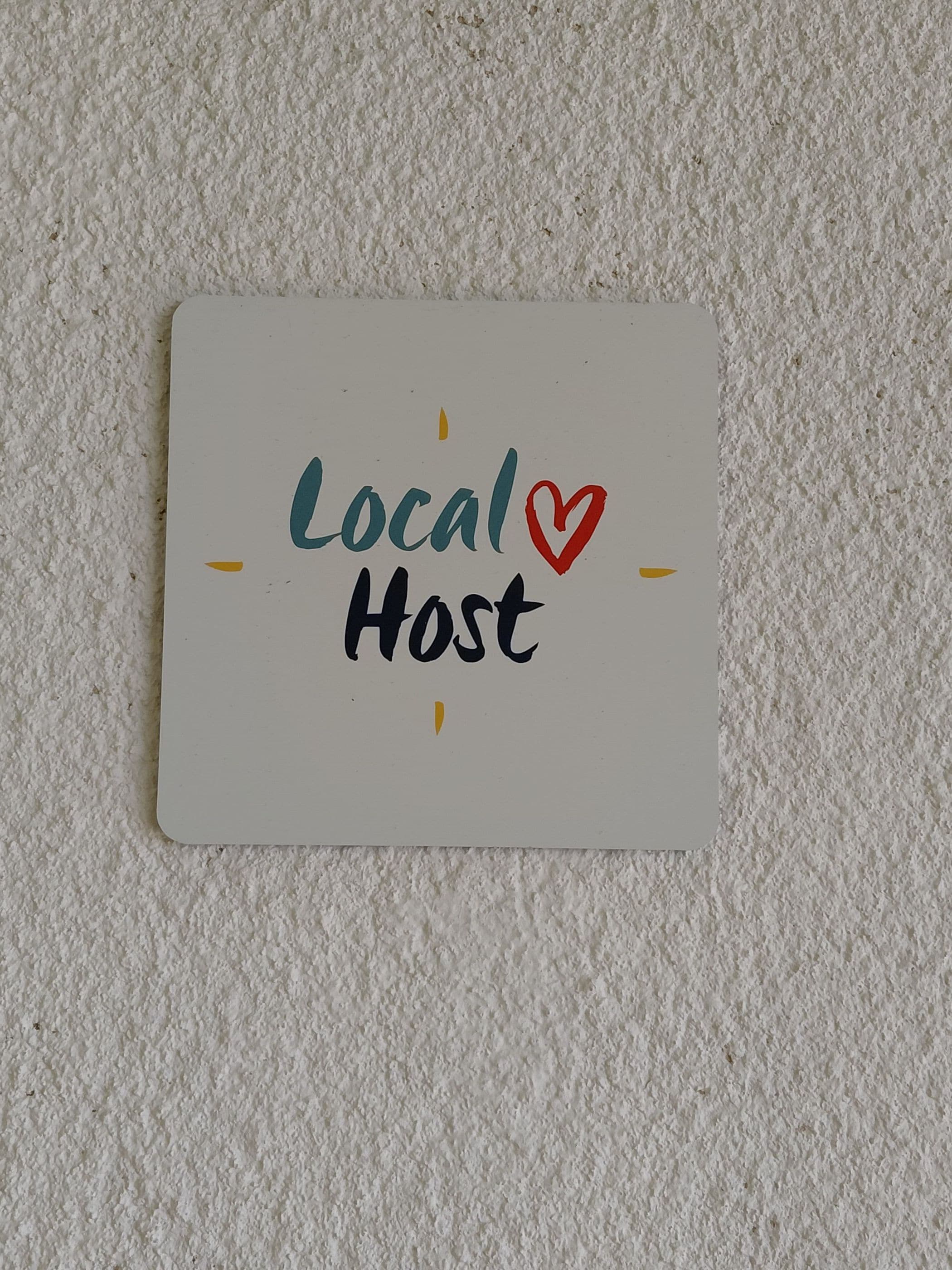A white sign with the words 'Local Host' written in black and teal, with a red heart symbol.