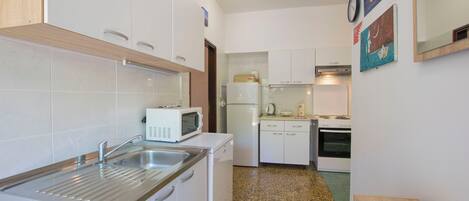 A compact kitchen with white appliances, a sink, and a small countertop.