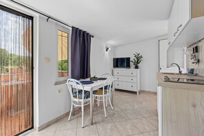 A compact kitchen with a dining area, a TV, and a sliding glass door to an outdoor area. - Apartments Villa Amaryllis (Brtonigla)