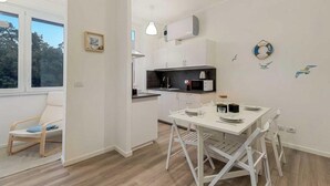 Een moderne keuken met witte kastjes, een eettafel met stoelen en uitzicht op de omgeving.