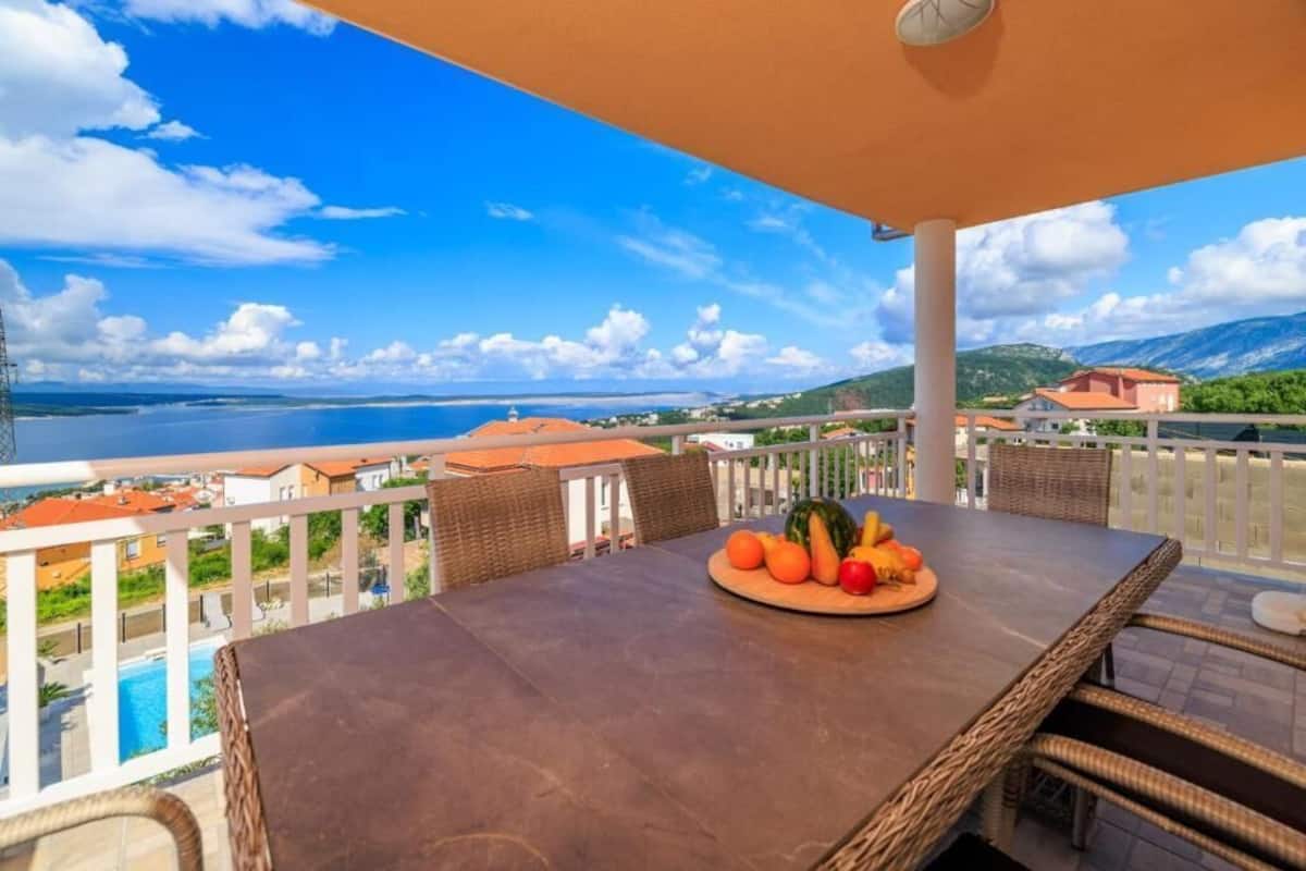 Eine Terrasse mit gedecktem Tisch, mit Blick auf ein Gewässer und eine Küstenstadt.