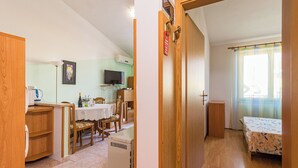 Una stanza compatta con un letto, un tavolino e una televisione.