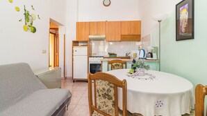 Una cucina compatta con mobili in legno, un tavolo da pranzo con tovaglia bianca e un divano nella zona soggiorno.
