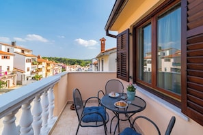 Ein Balkon mit Tisch, Stühlen und einer Topfpflanze.