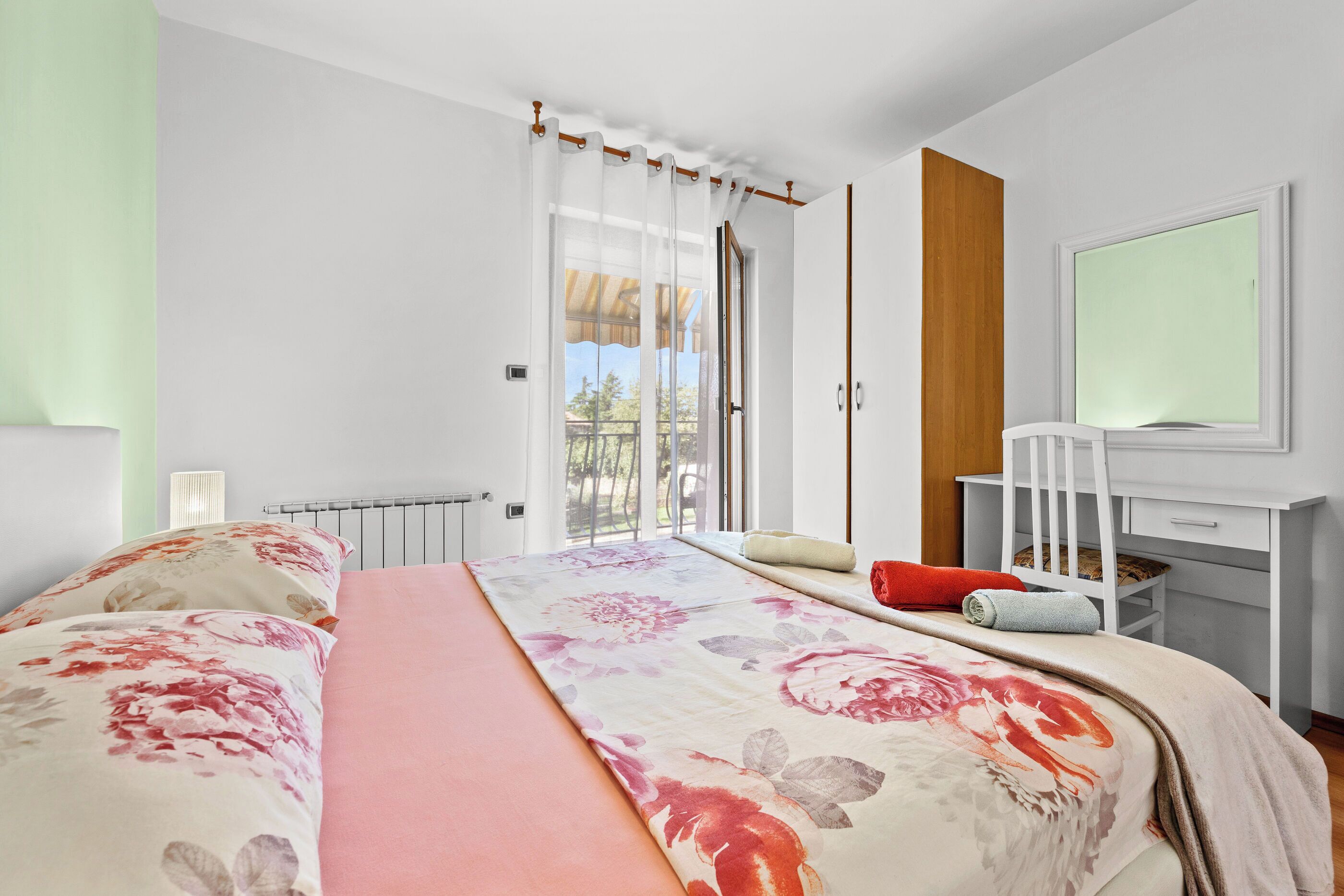Une chambre à coucher avec un grand lit, un bureau et une fenêtre avec des rideaux.