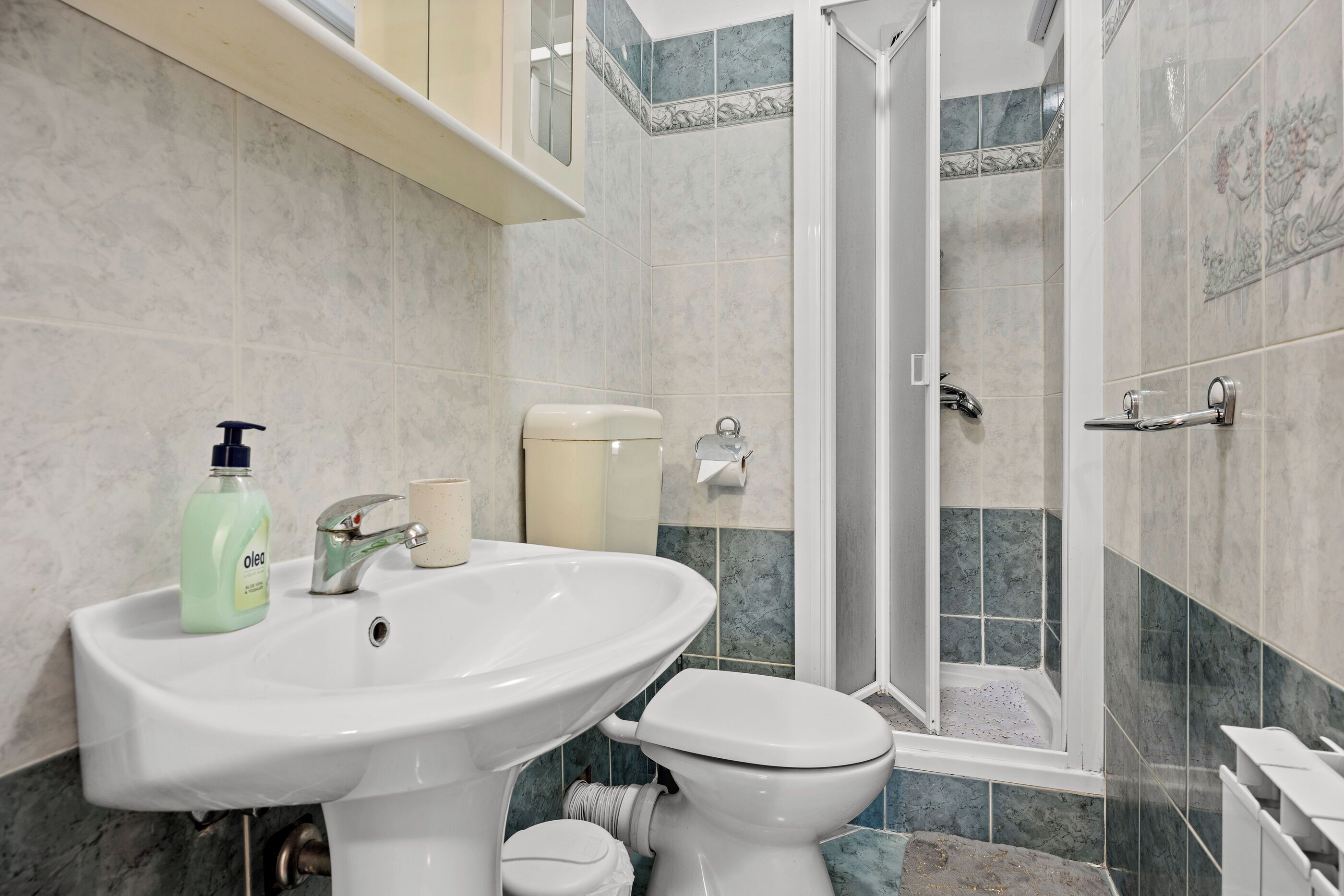 A bathroom with a white sink, toilet, and shower.