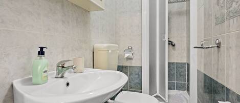 A bathroom with a white sink, toilet, and shower.