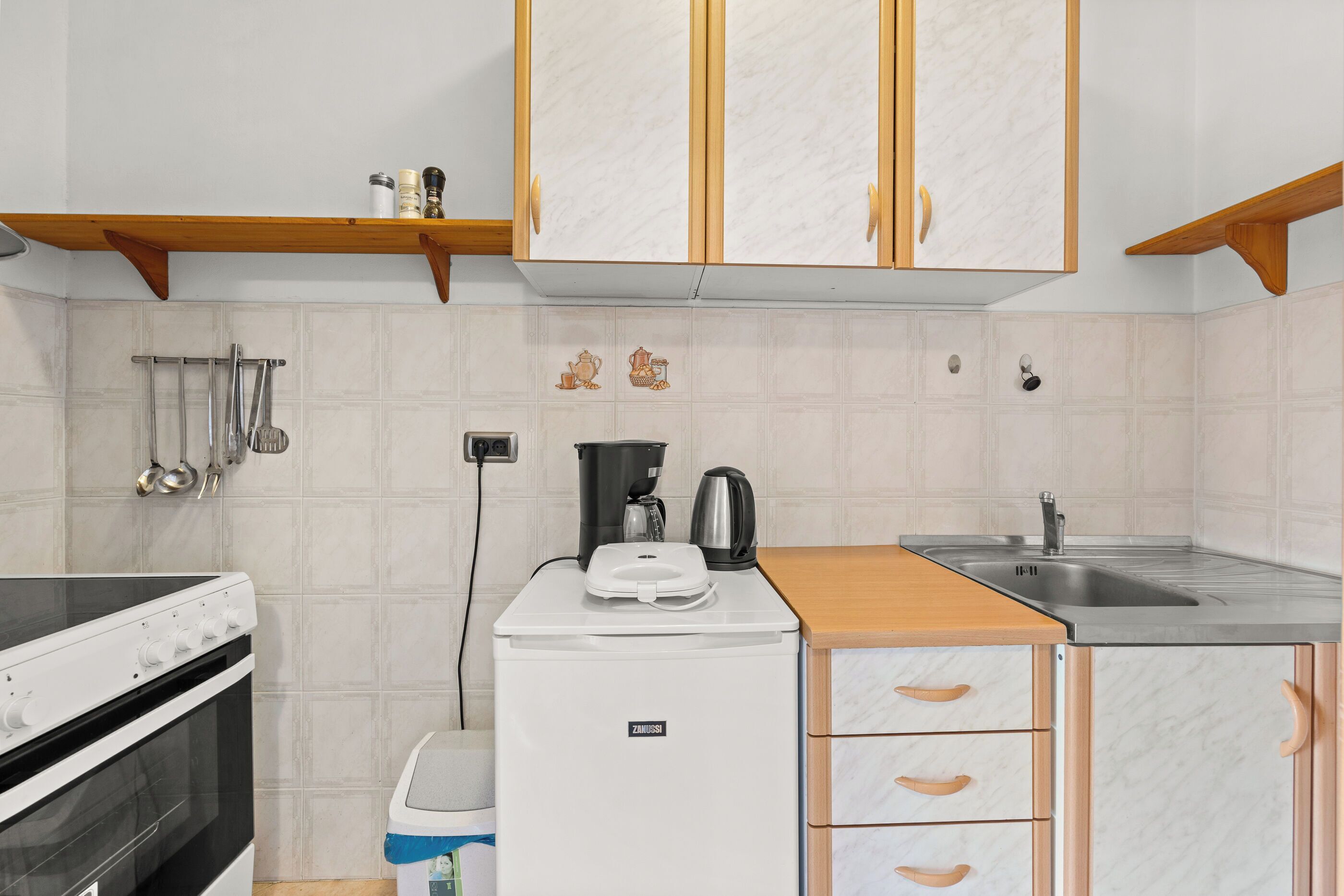 A compact kitchen with a stove, refrigerator, and sink.